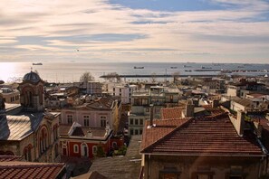 Un paysage urbain côtier avec des bâtiments historiques, une église imposante et une vue sur la mer avec des bateaux.