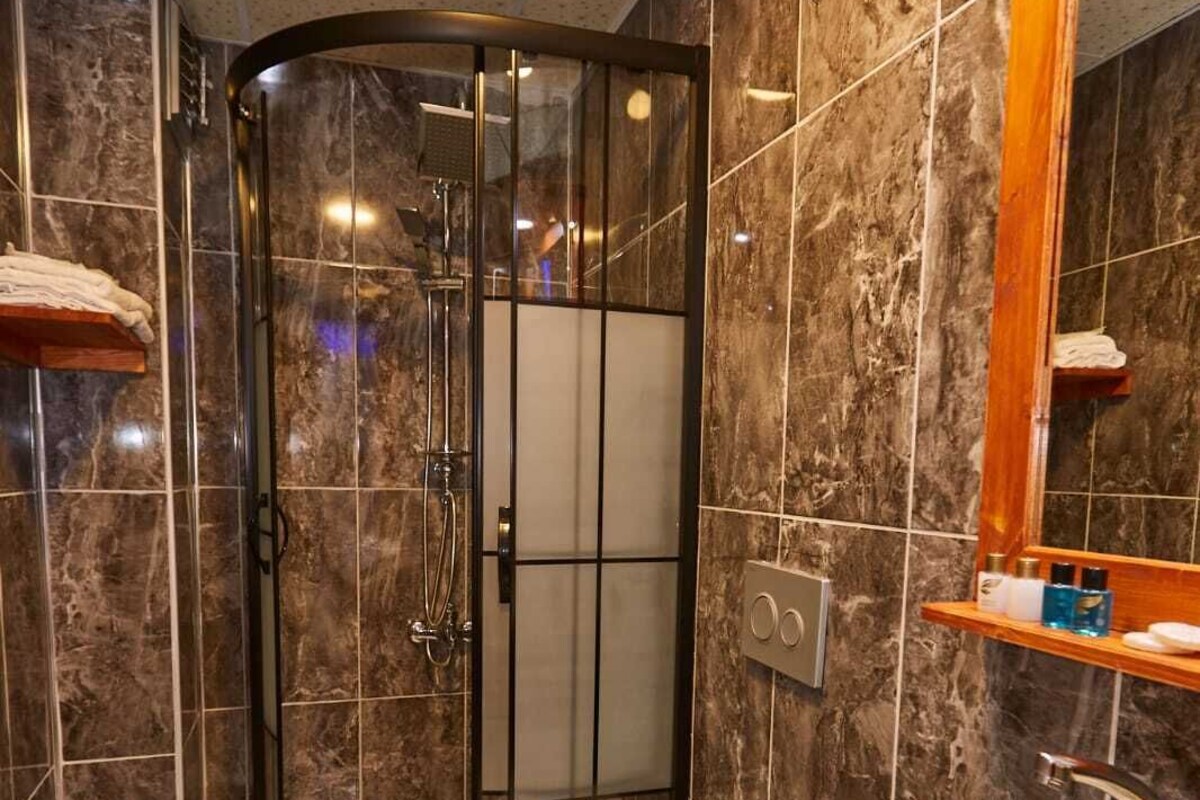 Une salle de bain avec une douche à parois de verre, des toilettes et un lavabo avec un miroir au-dessus.