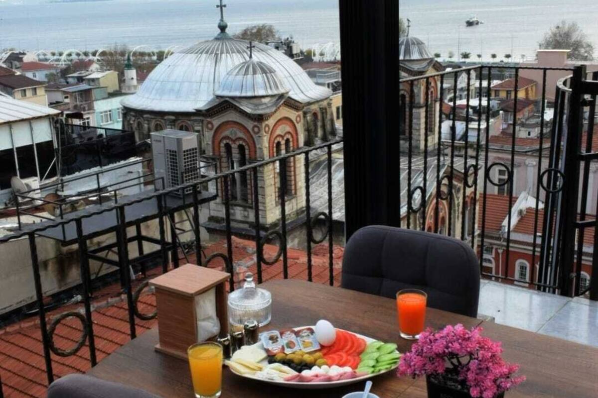 Een balkon met een ontbijttafel, met uitzicht op een stadsgezicht met een kerk en de zee.