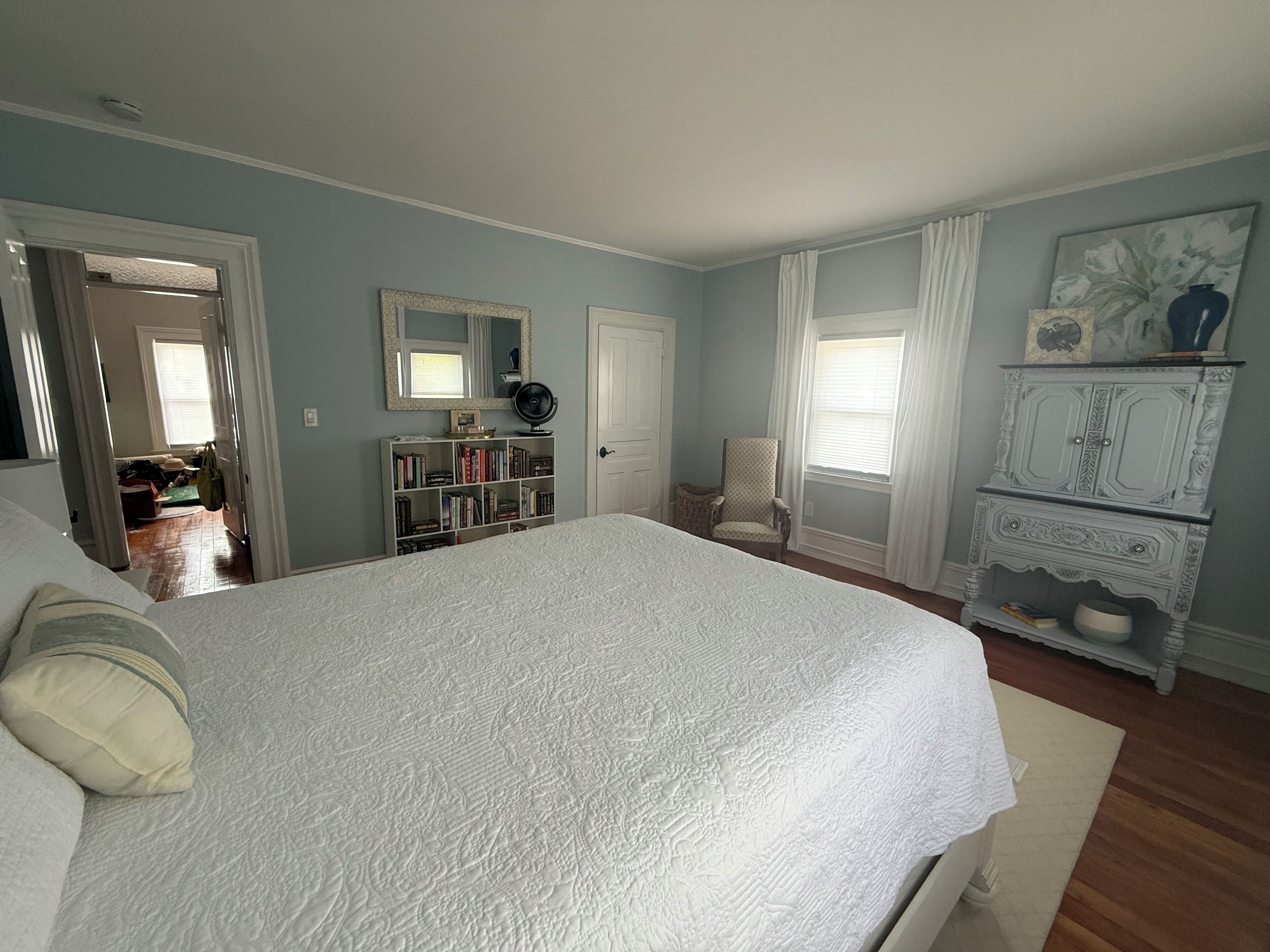 Una camera da letto con un letto grande, una cassettiera, una sedia e una libreria.