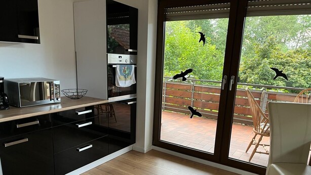 A modern kitchen with a large window, a microwave, and a coffee maker. - Apartment in Hallstadt by Bamberg the world heritage City (Hallstadt)