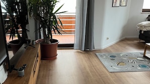 A modern living room with wooden flooring, a large potted plant, a flat-screen TV, and a sofa. - Apartment in Hallstadt by Bamberg the world heritage City (Hallstadt)
