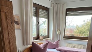 A bedroom with a wooden bed, two windows with blinds, a radiator, and a potted plant on the windowsill. - Apartment in Hallstadt by Bamberg the world heritage City (Hallstadt)