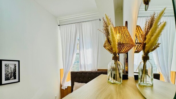 A modern room with a large mirror, a wooden table, and a bed with a black headboard. - 10 Economy Rooms-Shared Bath & Kitchen (Vienna)