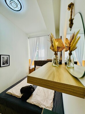 A modern room with a large mirror, a wooden table, and a bed with a black headboard. - 10 Economy Rooms-Shared Bath & Kitchen (Vienna)