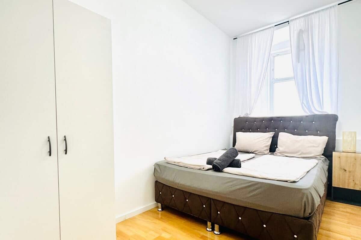 A bedroom with a bed, a wardrobe, and a window with curtains.
