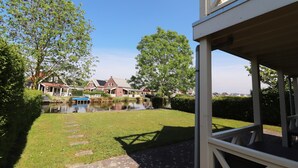 A residential area with a pond, pathway, and houses in the background. - Bungalow in South Holland With Private Jetty (Simonshaven)
