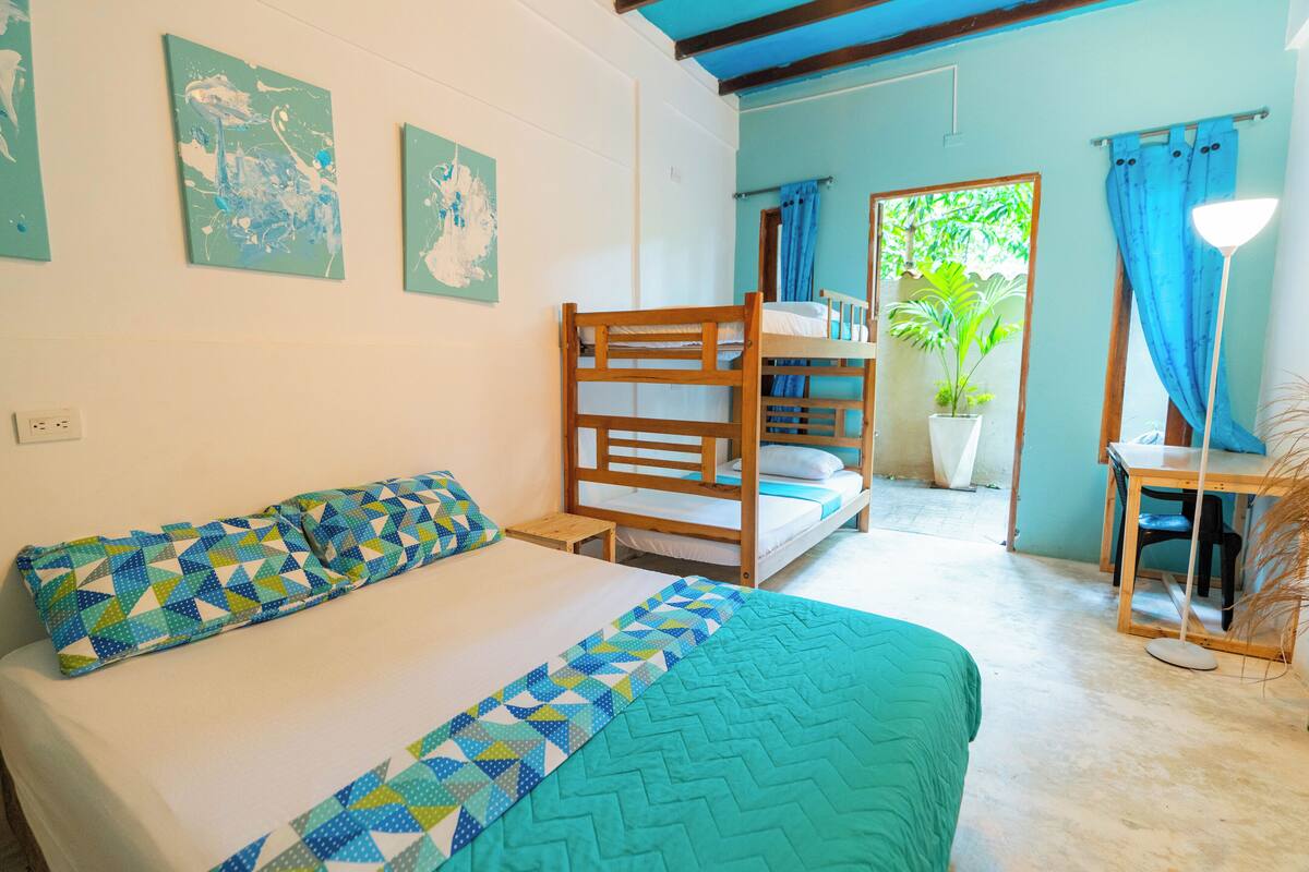 Una habitación con literas, un escritorio, una silla, una lámpara y una planta en maceta.