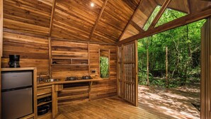 Una cabaña de madera con zona de cocina, que incluye un lavabo, estufa y refrigerador.