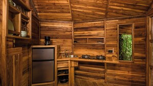 Interior de una cabaña de madera con refrigerador, pileta y estufa incorporados.