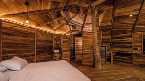 Interior de una cabaña de madera con una cama, una zona de estar pequeña y un kitchenette.