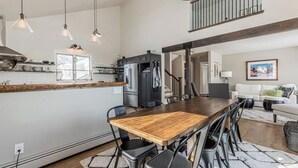 A spacious kitchen with a wooden dining table and chairs, a built-in refrigerator, and pendant lighting.