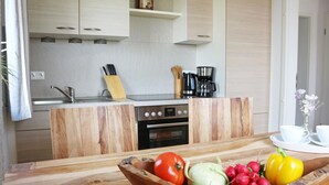 Cozinha moderna com armários de madeira, fogão embutido e bancada de madeira com uma tigela de vegetais.