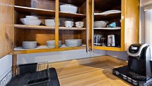 A compact kitchen with wooden cabinets, a coffee maker, and a dish rack. - Cozy and Convenient Family Getaway (DeKalb)