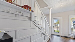 A staircase with white railings and a dark wooden floor leading to a door. - Cozy and Convenient Family Getaway (DeKalb)