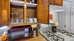 A kitchen with wooden cabinets, a microwave, a gas stove, and various kitchen utensils. - Cozy and Convenient Family Getaway (DeKalb)