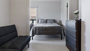 A bedroom with a bed, a dresser, a nightstand, and a window. - Cozy and Convenient Family Getaway (DeKalb)