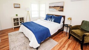 A bedroom with a bed, a nightstand, a chair, a window, and a wall-mounted air conditioner. - Quiet/charming 2-bedroom Sunset-Lake view cottage lovely Seneca lake, wine trail (Geneva)
