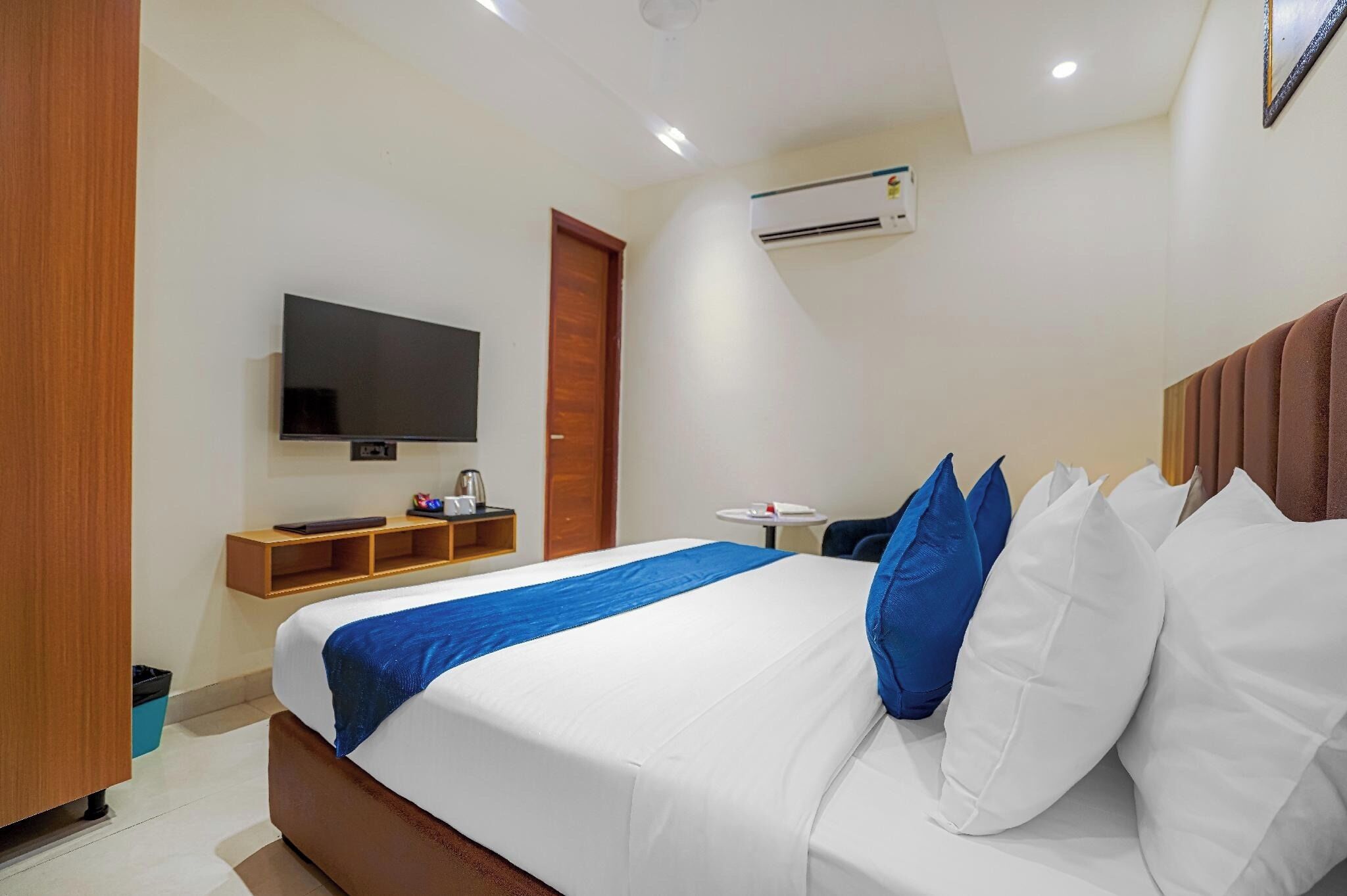 Ein Hotelzimmer mit Bett, Fernseher, kleinem Tisch und Klimaanlage.