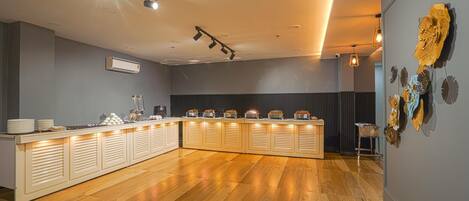 A modern kitchen with a long counter, overhead lighting, and decorative wall art.