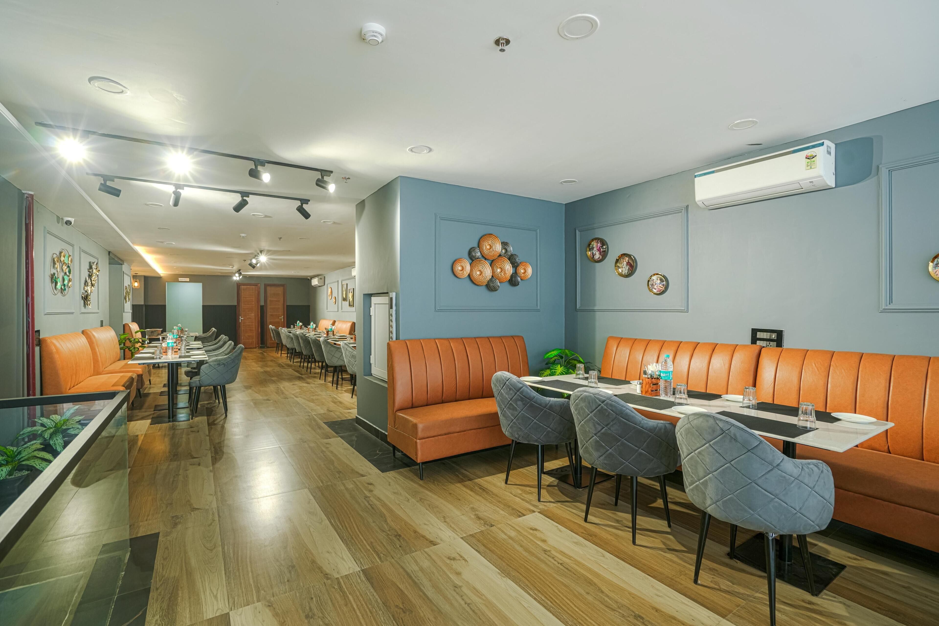 A modern restaurant with leather booths, grey upholstered chairs, and wooden flooring.
