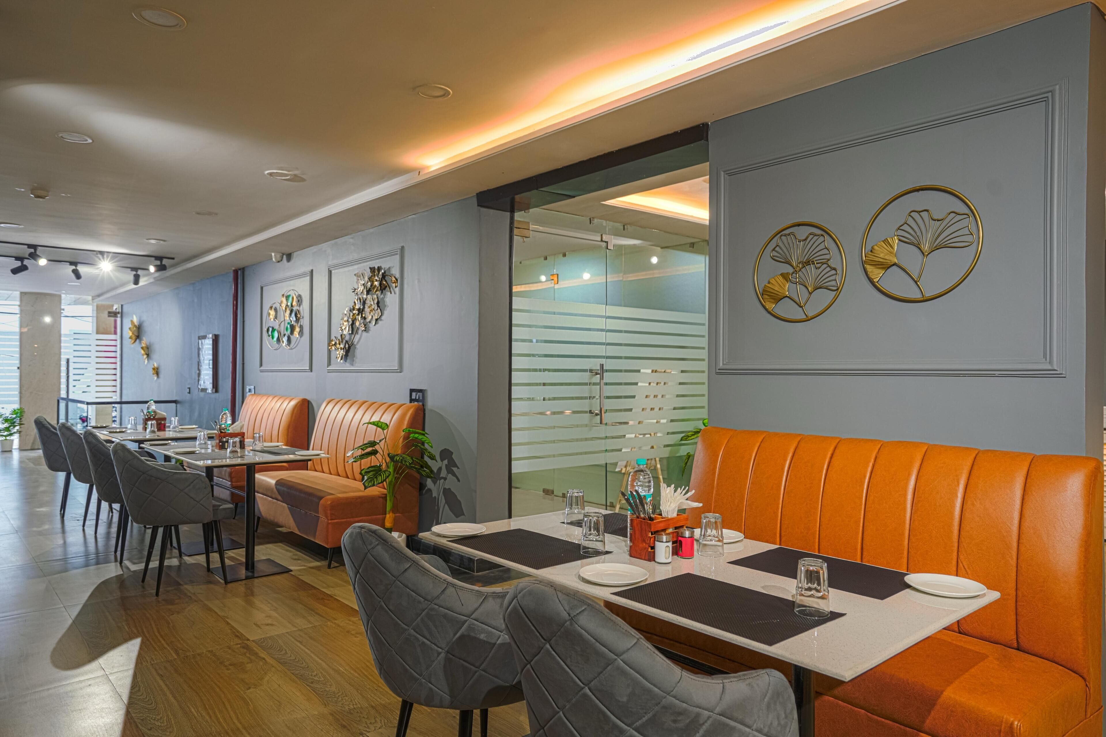 Ein modernes Restaurant mit einer langen Theke, orangefarbenen Sitzboxen und dekorativer Wandgestaltung.