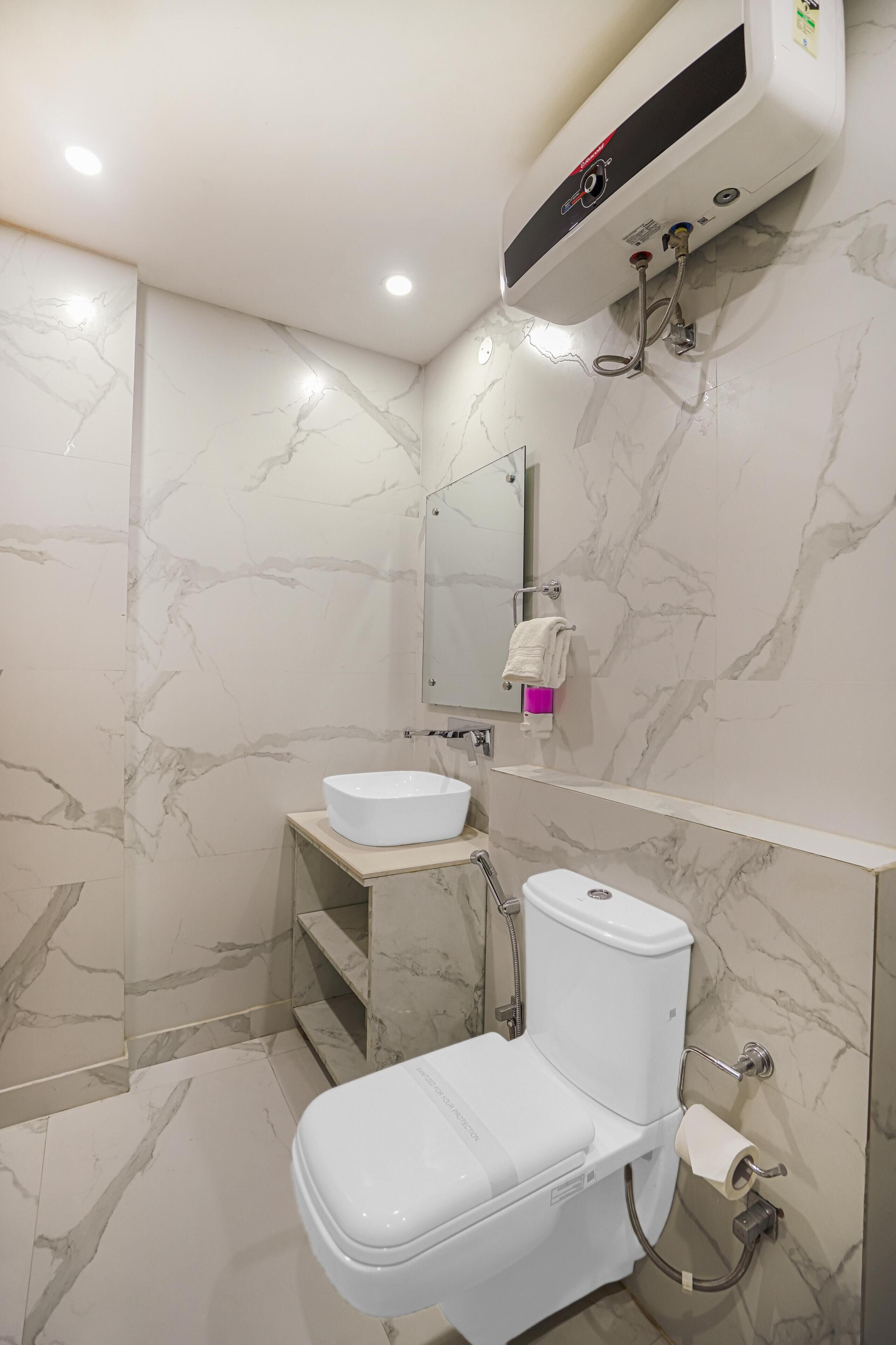 A modern bathroom with a white toilet, a sink with a marble countertop, and a wall-mounted mirror.