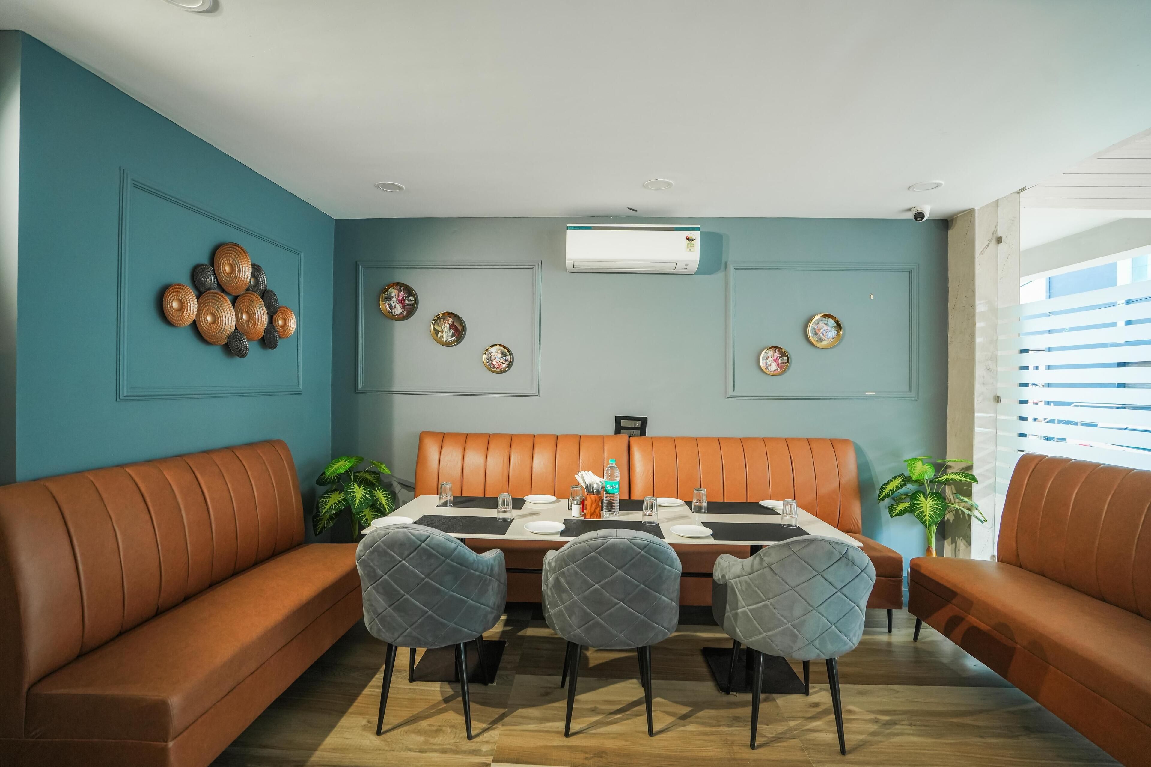 A dining area with a brown leather booth, a table set with plates and glasses, and decorative wall art.