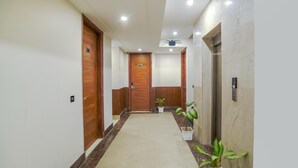 A hotel hallway with wooden doors, a marble floor, and potted plants. - Hotel Sky View - Zirakpur, Chandigarh (Dera Bassi)