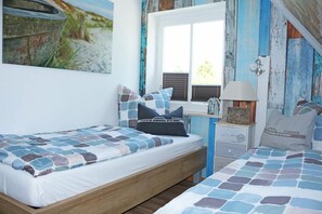 A bedroom with a bed, a nightstand, a window, and a painting on the wall. - Island idyll Villa Bullerbü (Fehmarn)