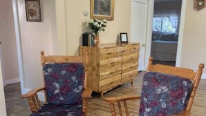 A room with two rocking chairs with floral upholstery, a wooden dresser, and a clock on the wall. - The Guesthouse (Great Falls)