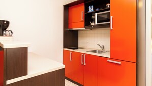 A modern kitchen with red cabinets, a stainless steel sink, and a coffee machine.