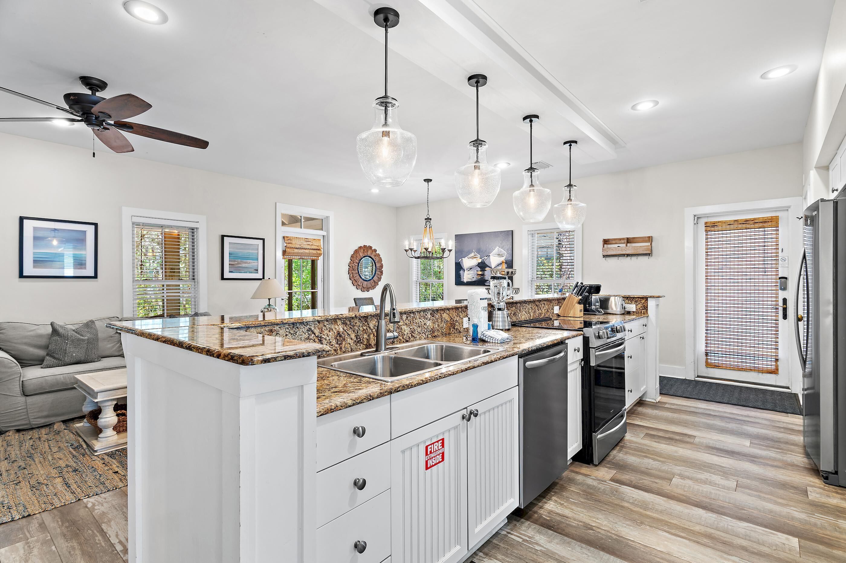 A modern kitchen with granite countertops, stainless steel appliances, and pendant lighting.