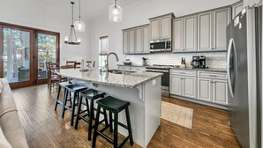 Una cucina moderna con isola centrale, elettrodomestici in acciaio inossidabile e un'area pranzo con sgabelli da bar.
