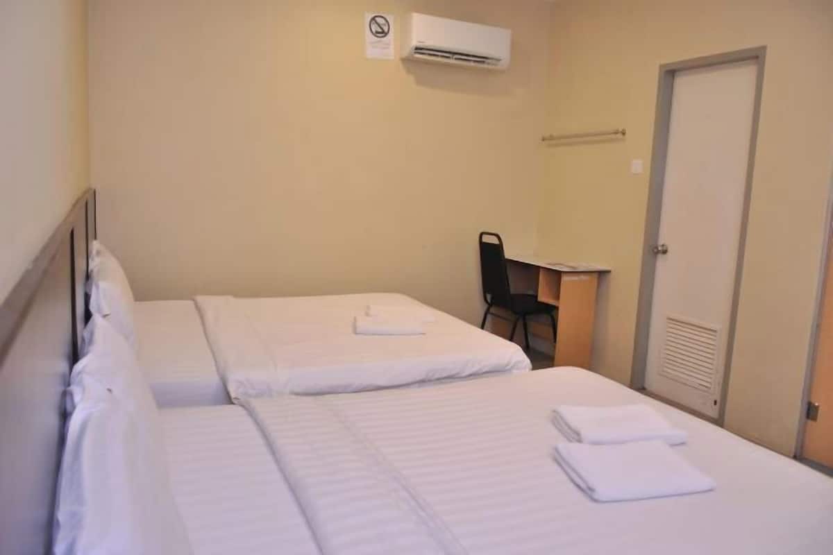 A hotel room with two beds, a desk, and a chair.