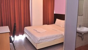 A hotel room with a bed, a desk, a chair, a sink, and a mirror. - Kuching Transit Inn (Kuching)