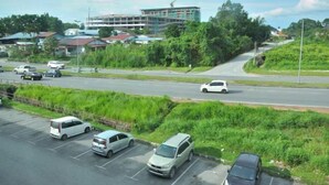 A parking lot with several cars and a building under construction in the background. - Kuching Transit Inn (Kuching)