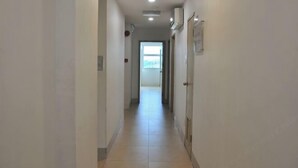 A long, narrow hallway with a tiled floor, white walls, and a door at the end. - Kuching Transit Inn (Kuching)