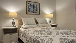 A neatly arranged bedroom with a bed, two bedside tables, and a wall-mounted artwork.