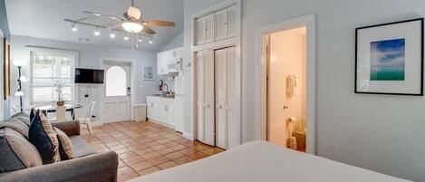 Une chambre d’hôtel de taille réduite comprenant un lit, une petite kitchenette, un coin repas et une salle de bain.