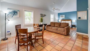 Un vaste espace de vie comprenant une table à manger, des chaises, un canapé et un ventilateur de plafond.