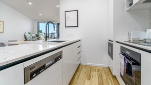 Eine moderne Küche mit weißen Schränken, einem Geschirrspüler, einem Backofen und einem Spülbecken.