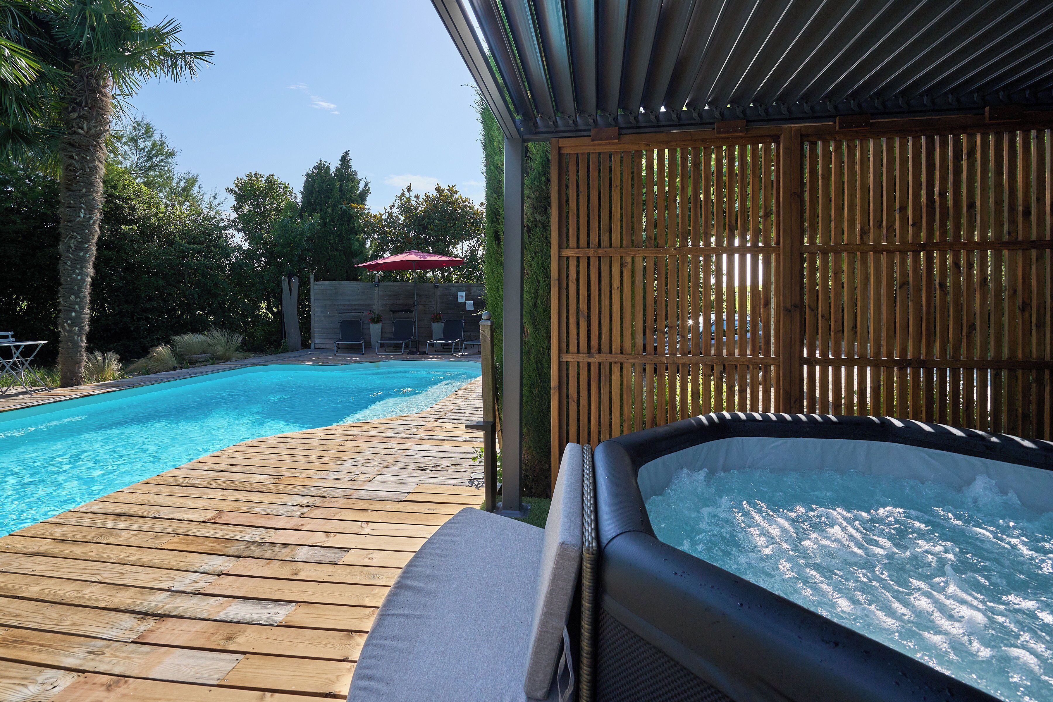 A wooden deck leading to a swimming pool with a hot tub.