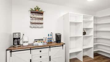 A kitchenette with a coffee maker, a coffee cup, and a shelf with mugs.