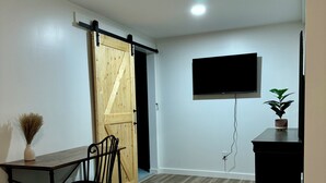 Un dormitorio con cama, escritorio, silla, televisor y puerta corredera.