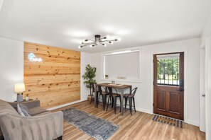 Un interior moderno con un muro decorativo de madera, una zona de comedor con sillas, un sofá y una alfombra.