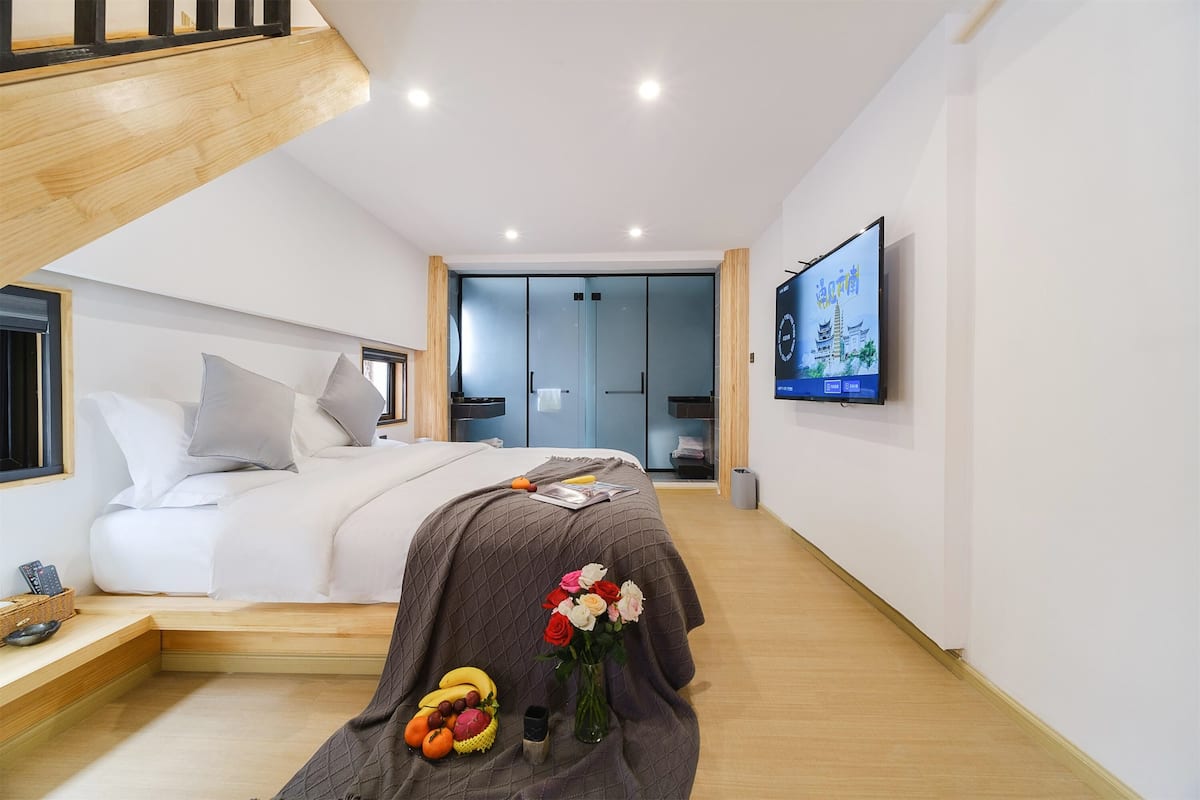 A modern bedroom with a bed, bedside table, and a TV mounted on the wall.