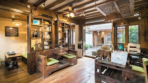 A rustic wooden interior with a wooden bench, shelves with various items, and a view of the outside. - Big Tree Guesthouse (Lijiang)