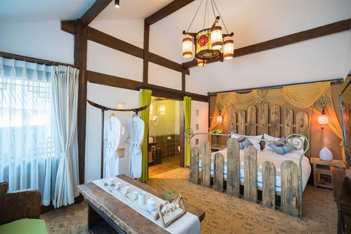A rustic room with a bed, wooden headboard, and a hanging light fixture.