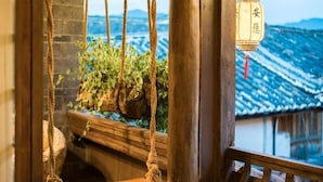 A wooden swing suspended by ropes, a wooden bench, and a hanging lantern with Chinese characters. - Big Tree Guesthouse (Lijiang)